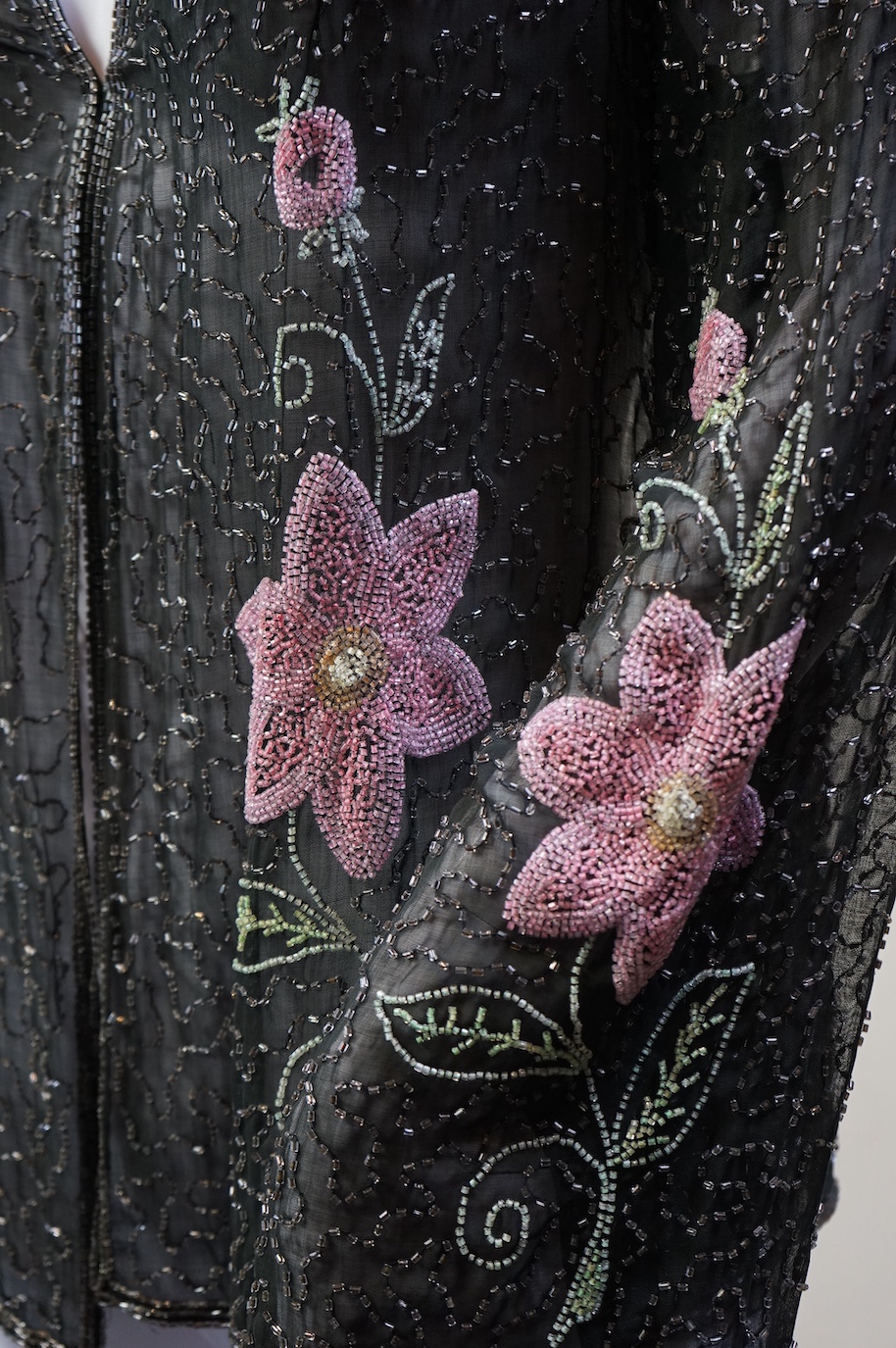 A 1930’s, multi coloured floral hand beaded evening jacket, the beading worked on black georgette. Possibly French, label on the inside of the neck 48. 64cm long. Condition - beading and georgette appear in good conditio